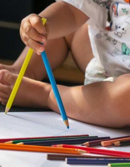girl in white and red hello kitty shirt holding blue pencil